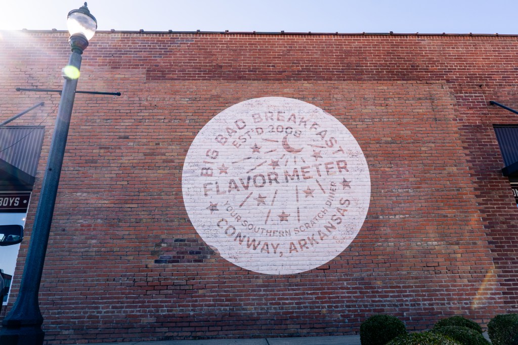 Mural on a brick wall promoting Big Bad Breakfast, established in 2008, featuring the tagline 'Flavor Meter' in Conway, Arkansas.